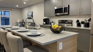 A modern kitchen with grey cabinets, stainless steel appliances, and a central island with seating. - Sky Ridge Heights| Outdoor Hot Tub | Parking (Harvie Heights)