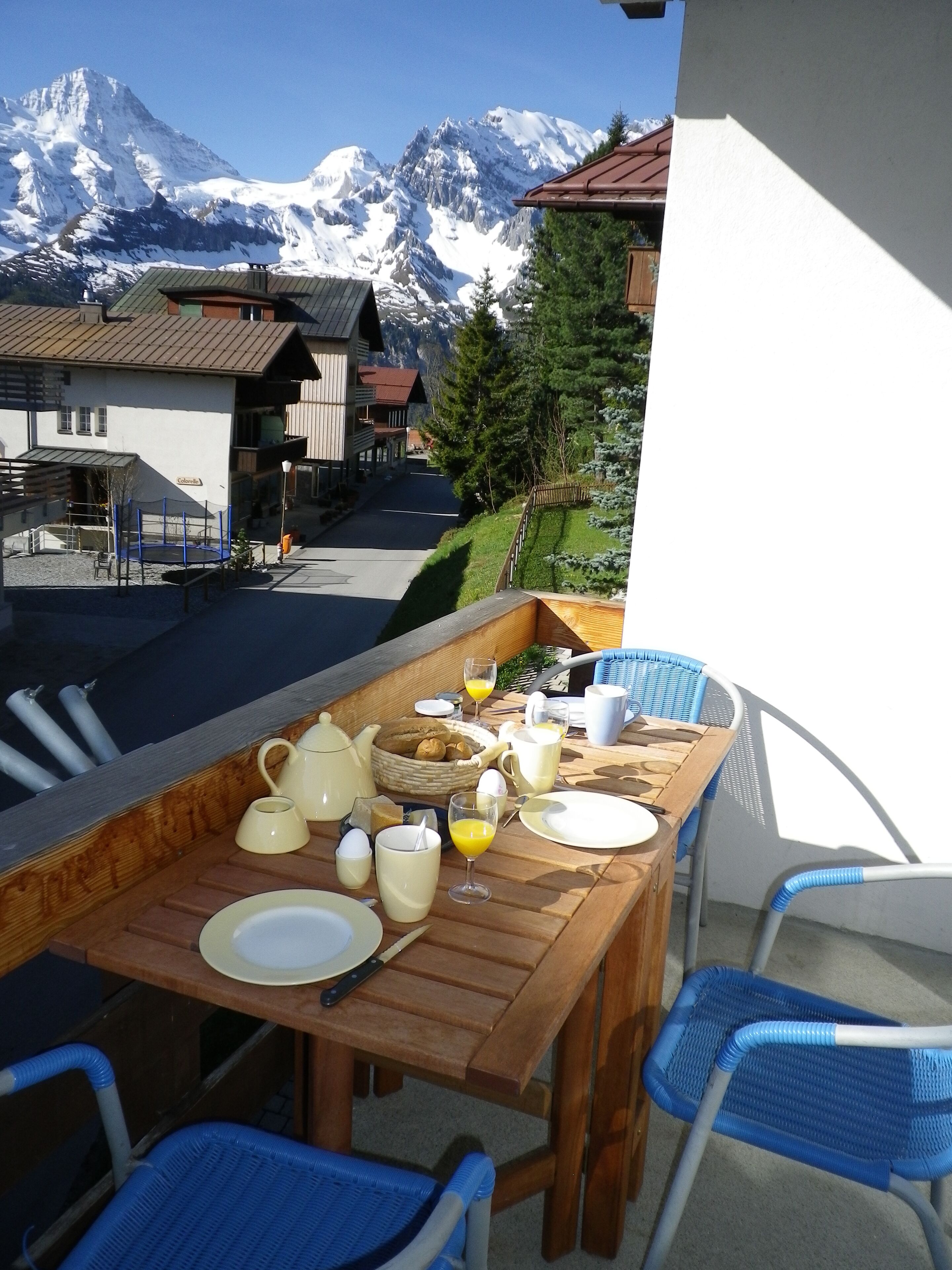Mesa de madera dispuesta para el desayuno, con vistas a la montaña.