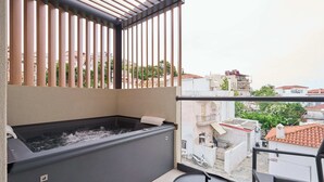A balcony with a hot tub, a small table, and a view of the cityscape. - Skiathos Senses (Skiathos)