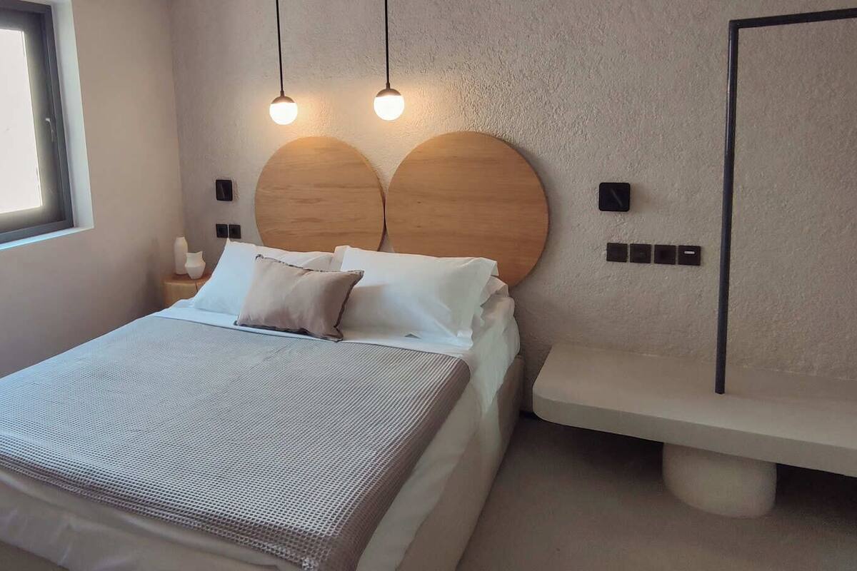 A bedroom with a bed, bedside tables, a bench, and a window.
