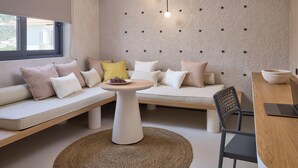 A modern living room with a sofa, a round table, and a laptop on a wooden desk. - Skiathos Senses (Skiathos)