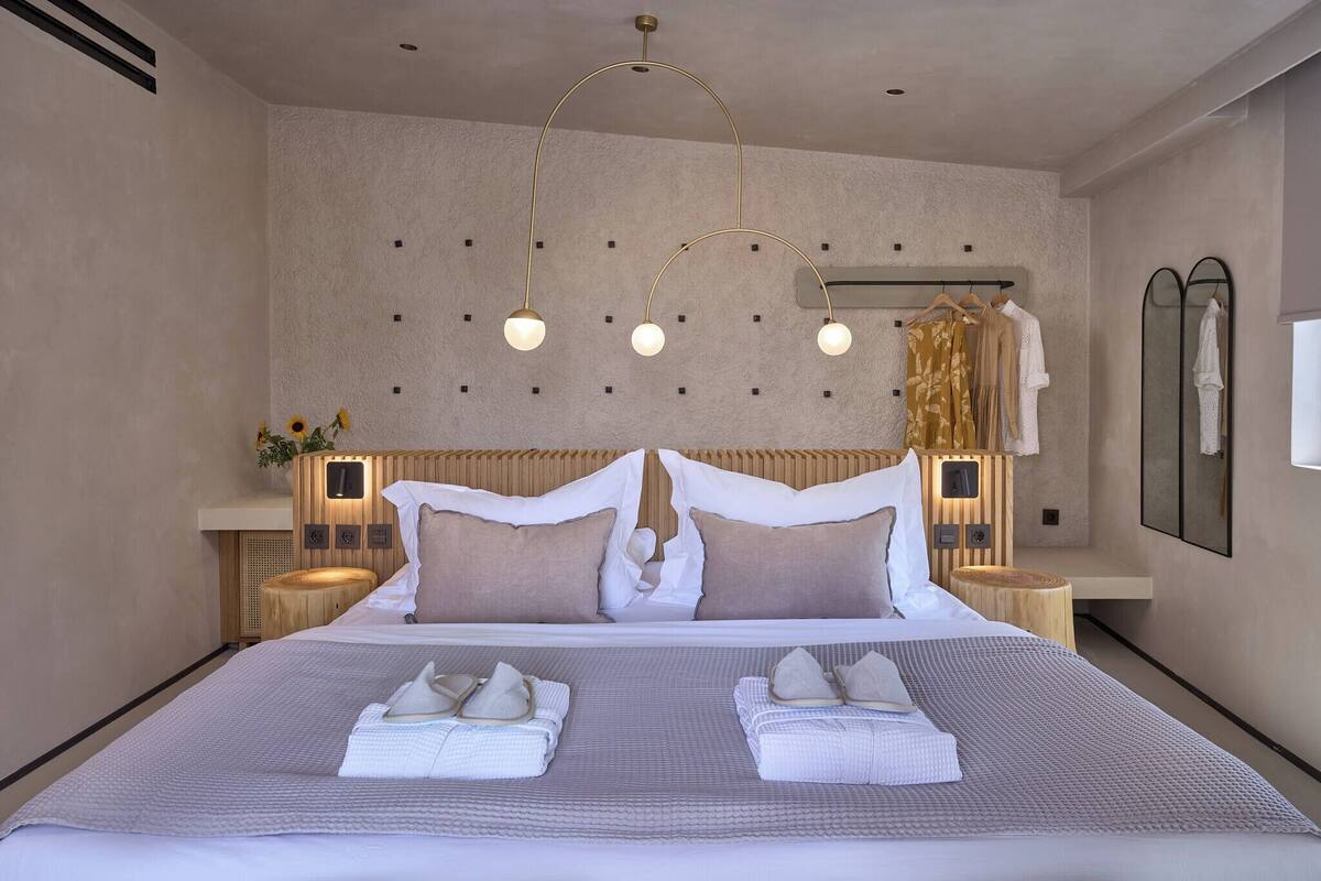A modern hotel room with a large bed, a wooden headboard, and a ceiling light fixture.