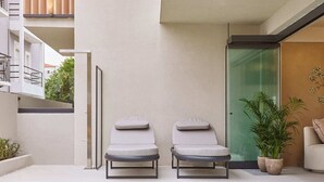 A modern outdoor pool area with two lounge chairs, a glass door, and a potted plant. - Skiathos Senses (Skiathos)