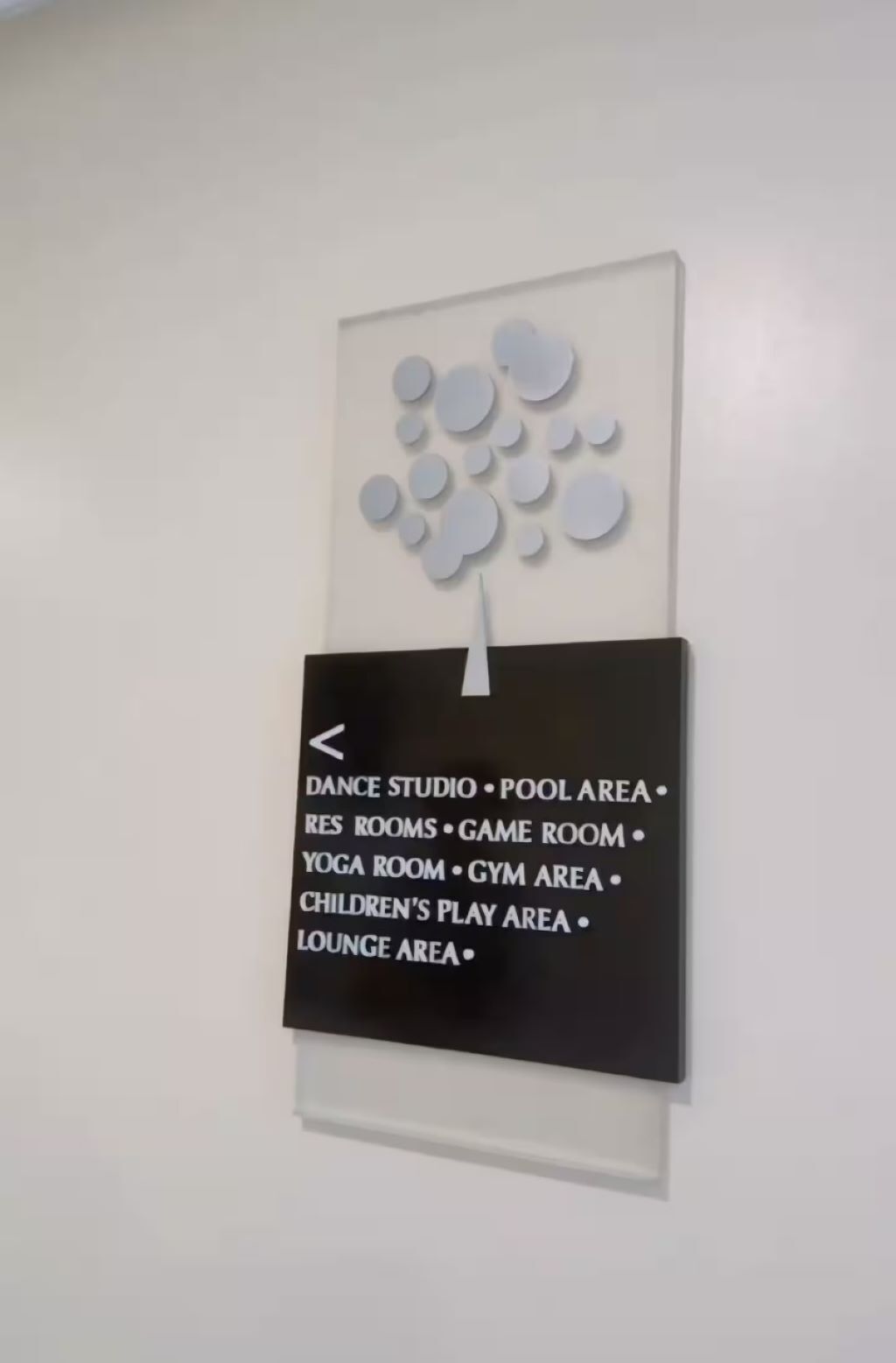A wall sign listing amenities including a dance studio, pool area, game room, yoga room, gym area, children's play area, and lounge area.