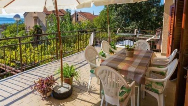 A terrace with a table and chairs, umbrellas, and potted plants.