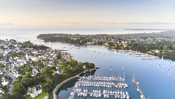 Une vue aérienne d’une marina où sont amarrés de nombreux bateaux, entourée de bâtiments résidentiels et de verdure.