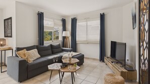 A modern living room with a grey sofa, a coffee table, and a TV.