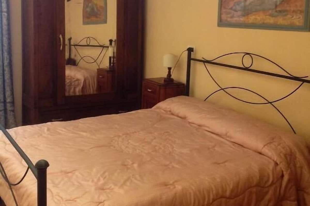 Une chambre à coucher avec un lit, une armoire, une table de chevet, une lampe et un tableau au mur.