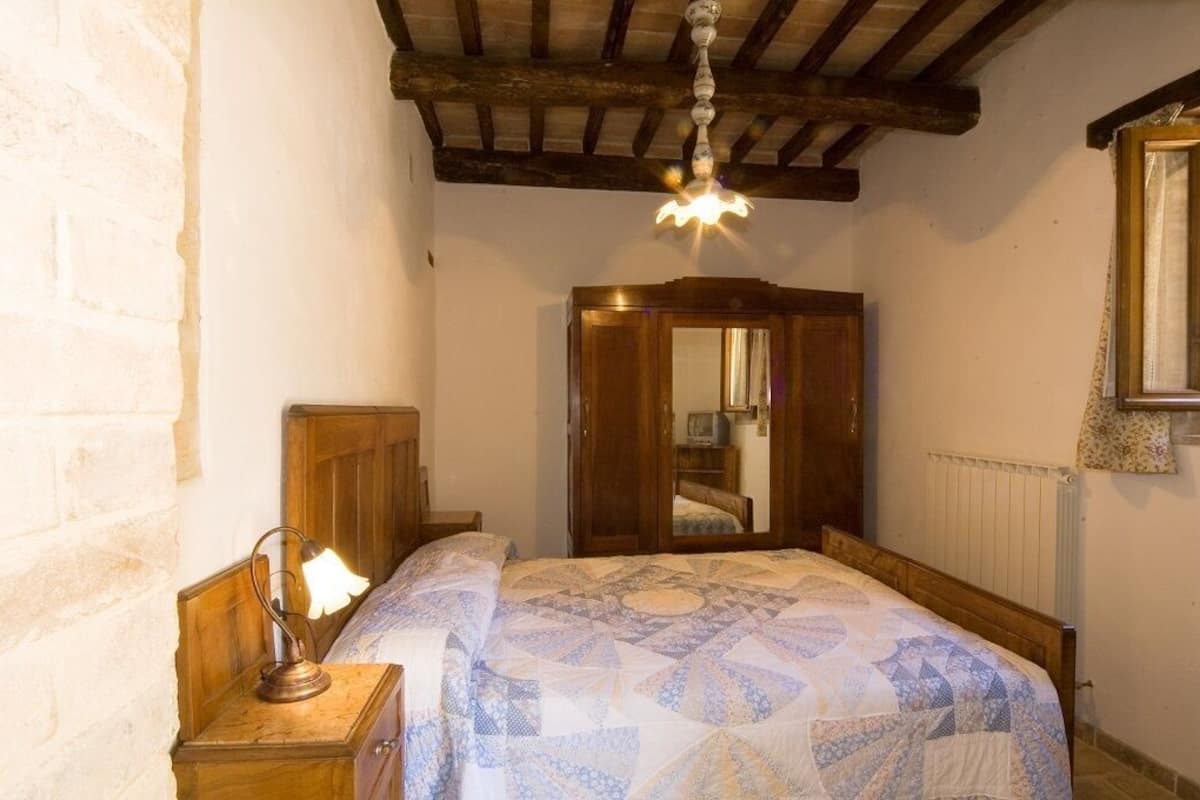 Une chambre à coucher avec un lit en bois, une table de chevet avec une lampe, une armoire et un miroir.
