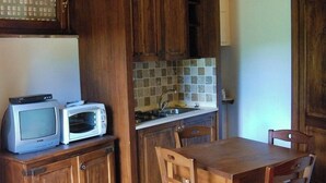 Een landelijke keuken met houten kastjes, een betegelde spatwand en een eettafel met stoelen.