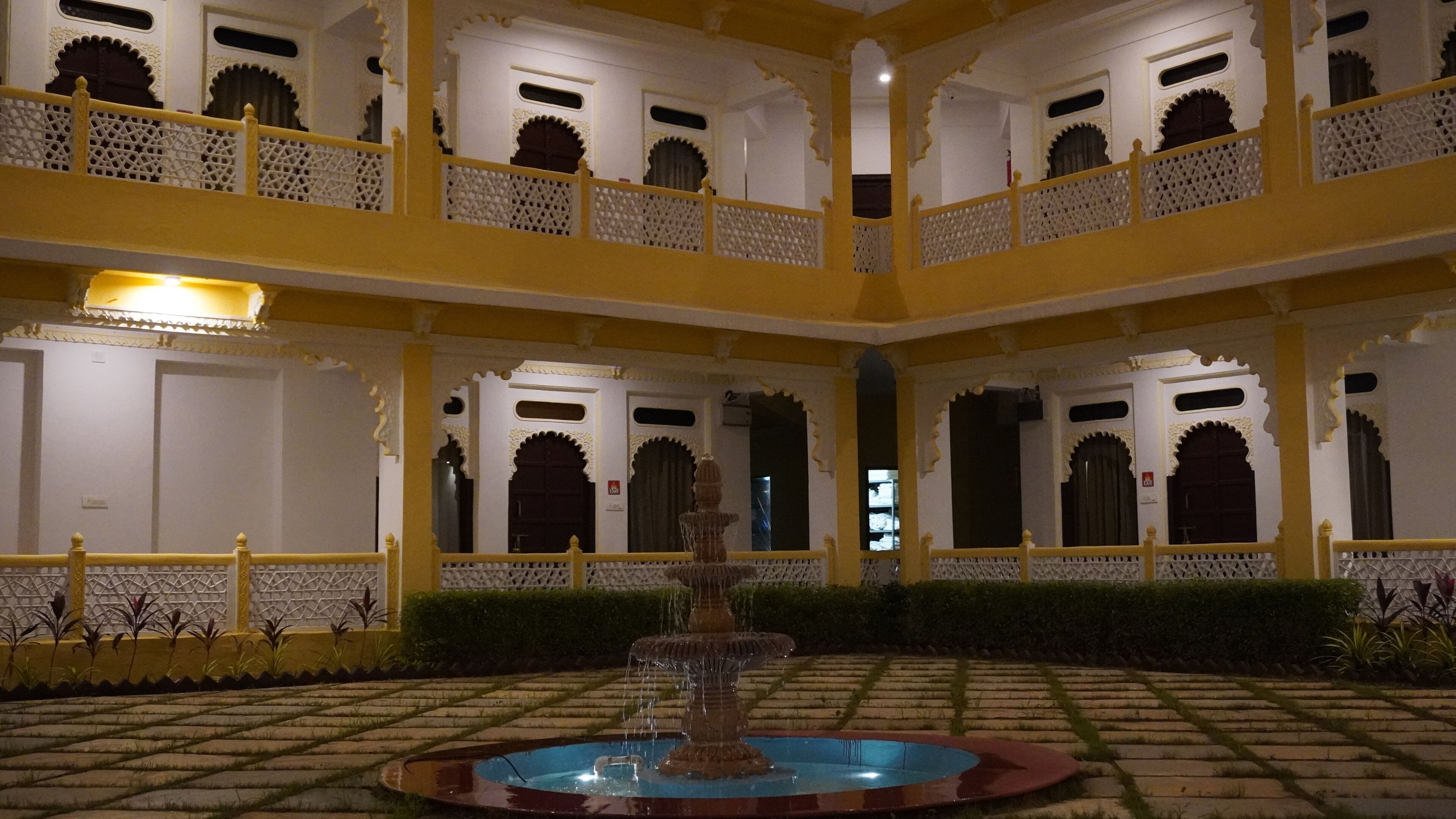 A multi-level courtyard with ornate balconies, a central fountain, and a patterned floor.