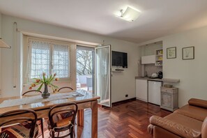 Relax in this open-plan living space with a dining area and kitchenette, featuring a sofa, dining table, and flat-screen TV.