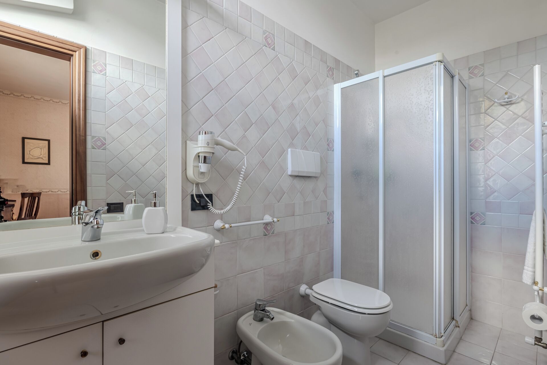 A bathroom with a sink, toilet, bidet, and a walk-in shower.