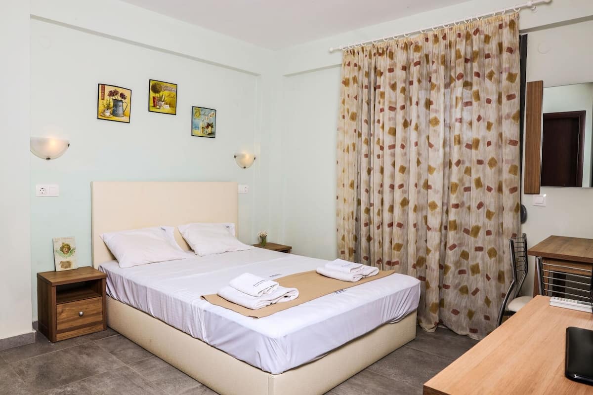 A hotel room with a bed, bedside tables, a desk, and a mirror.