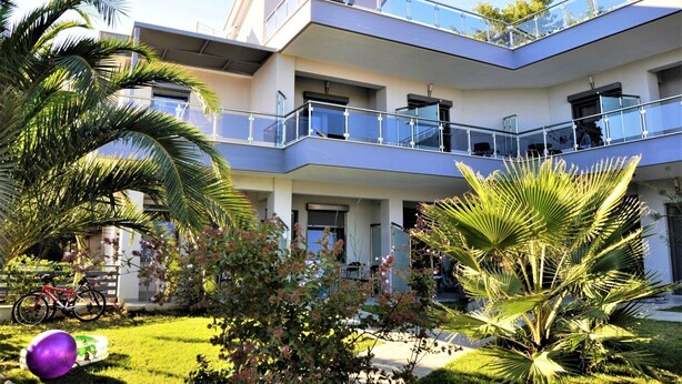 A modern multi-story building with balconies, a well-maintained garden, and a bicycle parked outside. - Aquarius Nikiti (Nikiti)