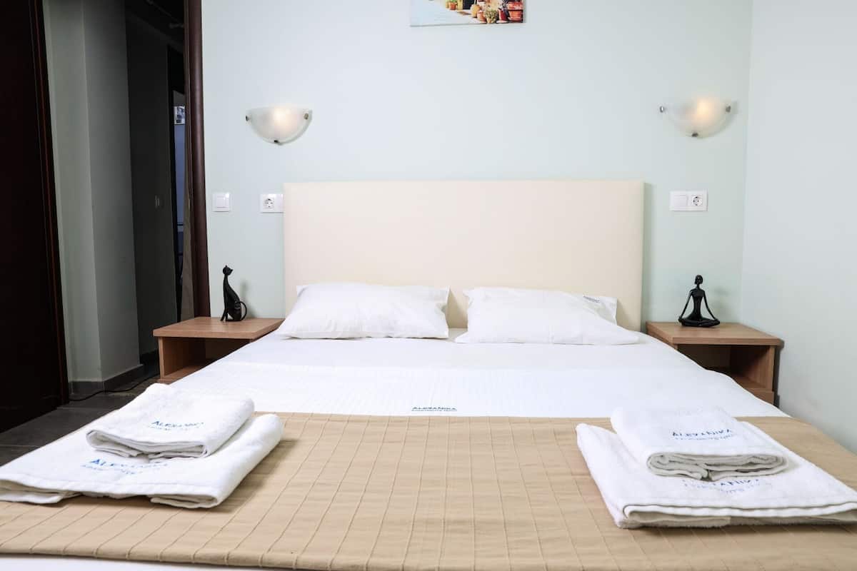A hotel room with a bed, two nightstands, and a wall-mounted light fixture.