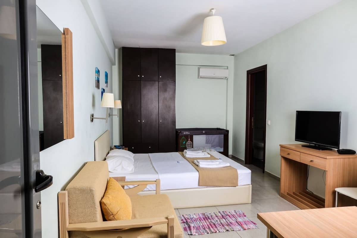 A hotel room with a bed, a desk, a television, a wardrobe, and a lamp.