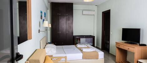 A hotel room with a bed, a desk, a television, a wardrobe, and a lamp.