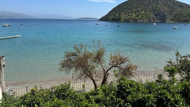 A coastal view with clear water, boats, and a hilly island.