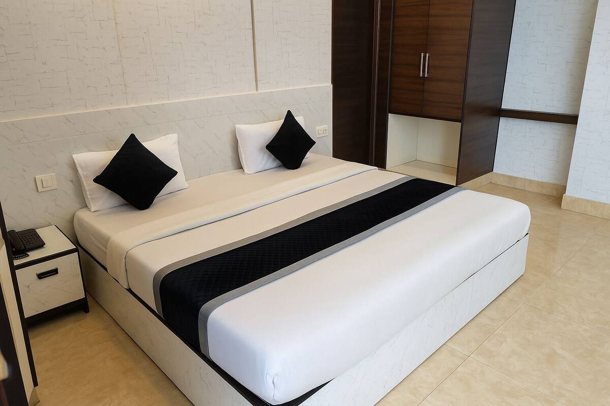 A modern bedroom with a large bed, a bedside table, and a wardrobe.