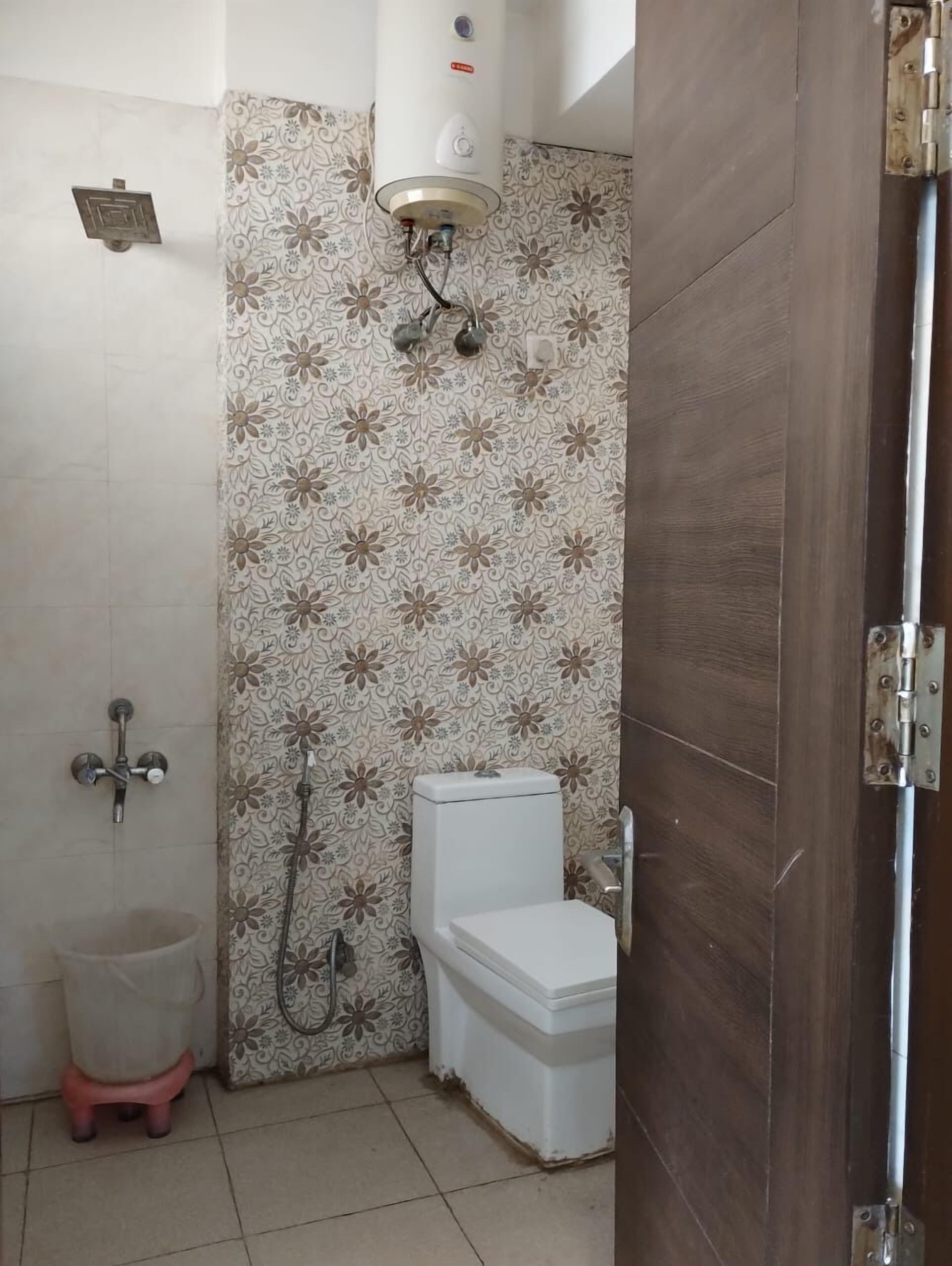 A bathroom with a shower, toilet, and a small stool.