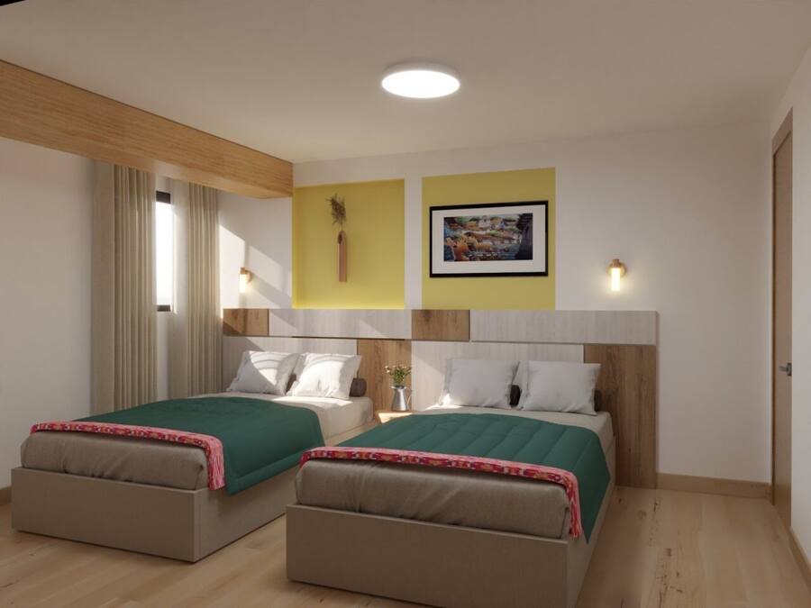 Quarto de hotel com duas camas, teto de madeira, parede amarela de destaque, quadro emoldurado e janela com cortinas.