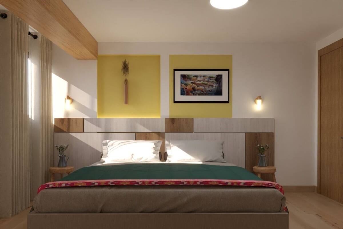 A modern bedroom with a large bed, two bedside tables, a yellow accent wall, and a framed picture above the bed.