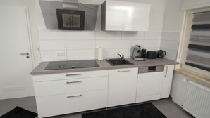 Eine moderne Küche mit weißen Schränken, einer Spüle, einem Backofen und einer Kaffeemaschine.