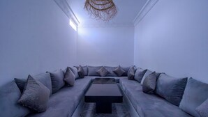 Un salon moderne avec un canapé d’angle, une table basse et un luminaire au plafond original.