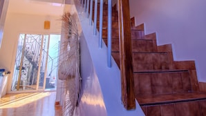 Un escalier avec des rampes en bois et des marches marron, menant à une pièce dotée d’une porte blanche et d’une porte en verre.