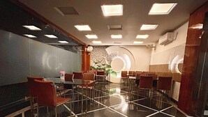 A conference room with a polished floor, multiple tables, and chairs arranged for meetings. - Hotel SHIVALAYA by GPH (Haridwar)