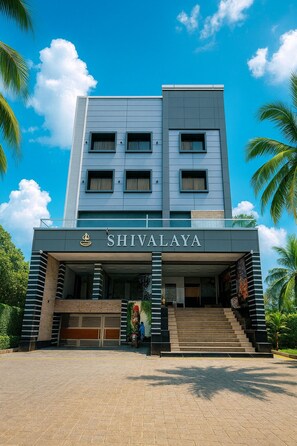 A modern hotel named SHIVALAYA with a prominent entrance, a staircase leading to the lobby, and a clear blue sky in the background. - Hotel SHIVALAYA by GPH (Haridwar)