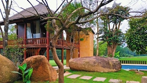 Una casa con una veranda in legno, grosse rocce e un prato.