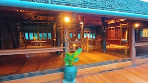 Una struttura in legno con un portico coperto, area salotto interna e una pianta in vaso.