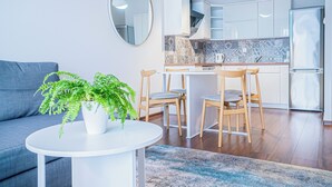 A modern kitchen with white cabinets, a marble backsplash, and a stainless steel refrigerator.
