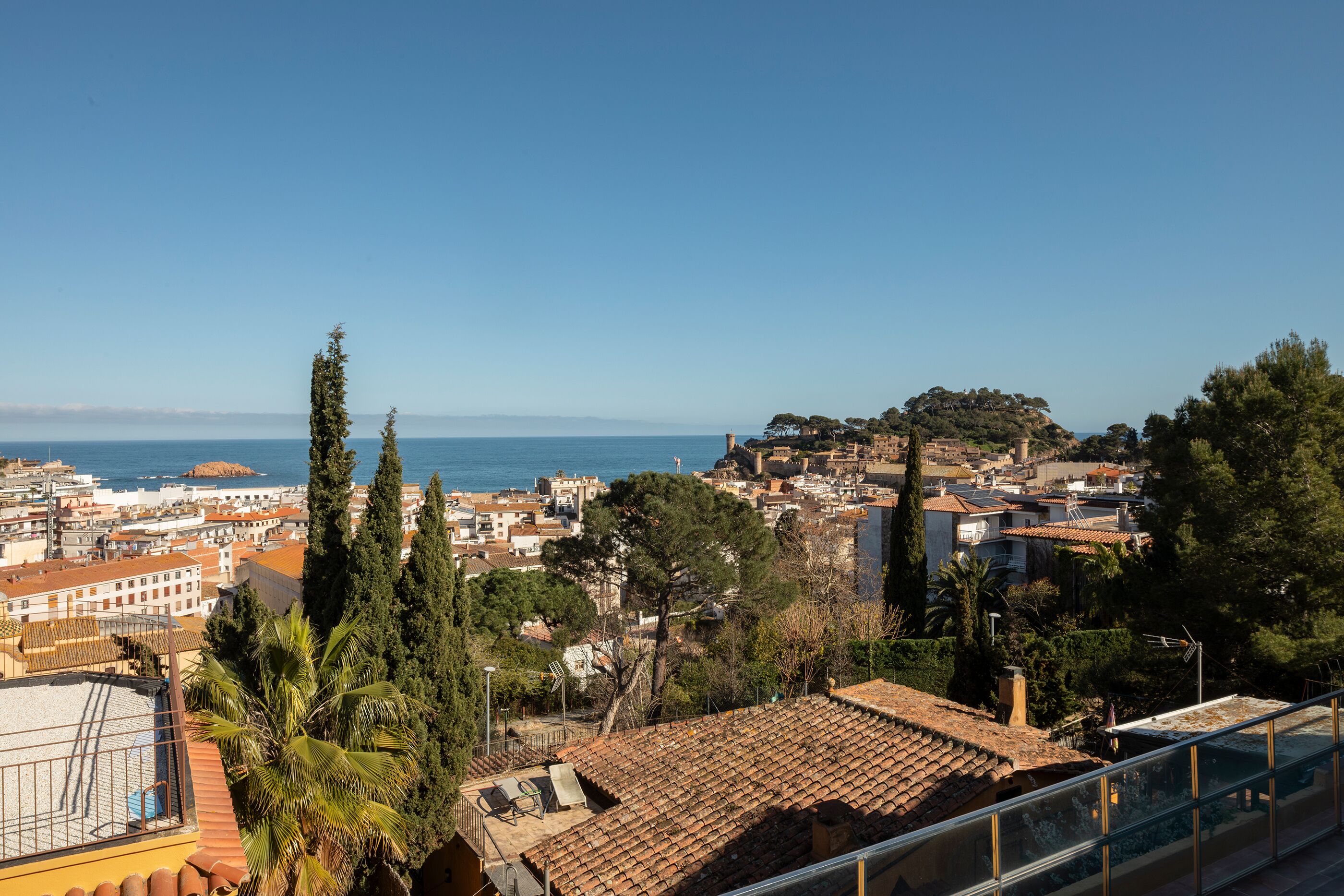A coastal cityscape with buildings, trees, and a clear sky.