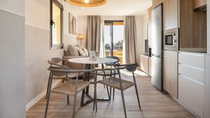 Eine moderne Küche mit Essbereich, einer Couch und Blick ins Freie.