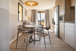 Eine moderne Küche mit Essbereich, einer Couch und Blick ins Freie.
