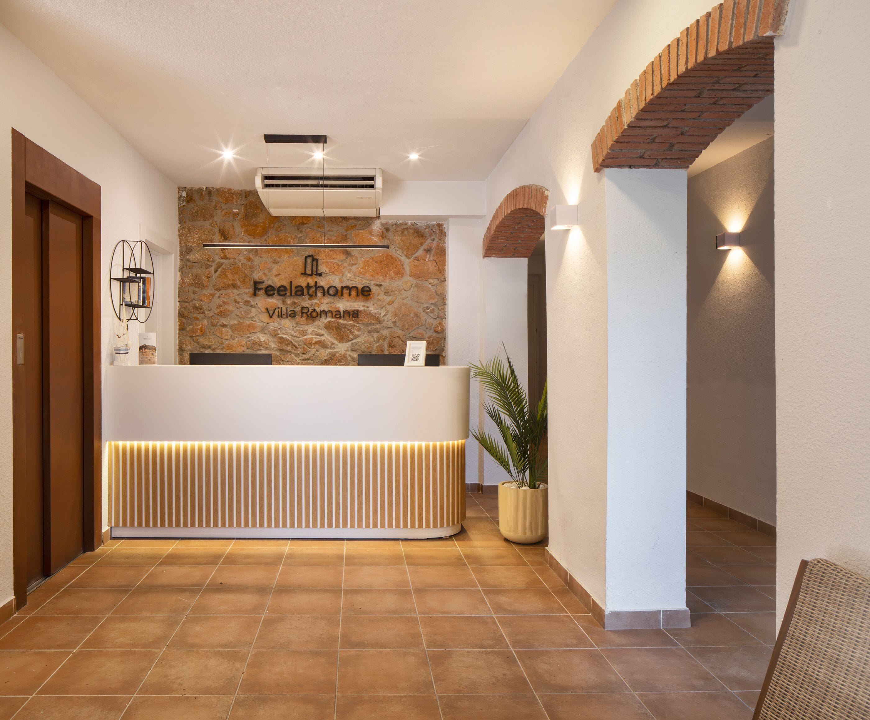 A reception desk with a stone wall backdrop, a modern air conditioning unit, and a potted plant.