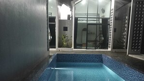A swimming pool with a tiled edge and a small adjacent seating area. - Sovilla II Yogyakarta (Depok)