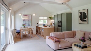 Amplia sala de estar con un sofá grande, una mesa de comedor con sillas, una cocina con electrodomésticos modernos y un ventanal que proporciona luz natural.