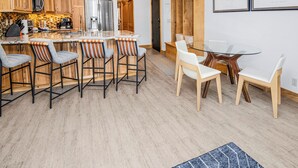 Une cuisine moderne avec des meubles en bois, un réfrigérateur en acier inoxydable et un coin bar avec des tabourets.