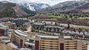 Un hôtel moderne à plusieurs étages, doté d’un parking et offrant une vue sur des montagnes enneigées en arrière-plan.