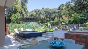 Une terrasse extérieure avec une table, des chaises et un jacuzzi.