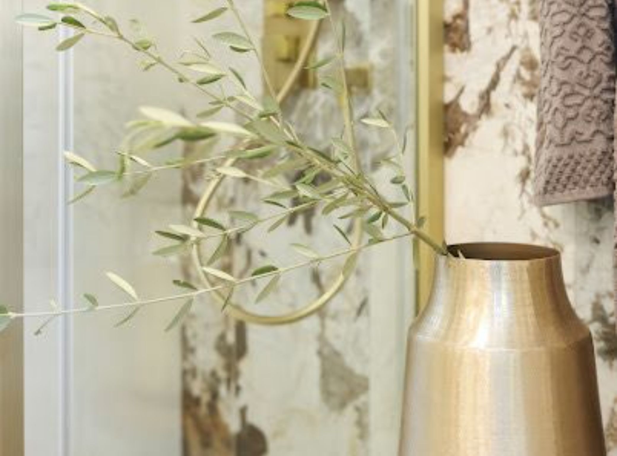 A vase with a branch of green leaves.