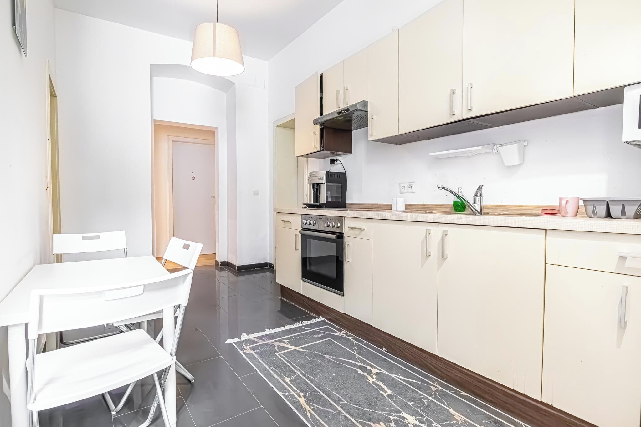 Cocina compacta con comedor, que incluye una mesa, sillas, una cafetera y un microondas.