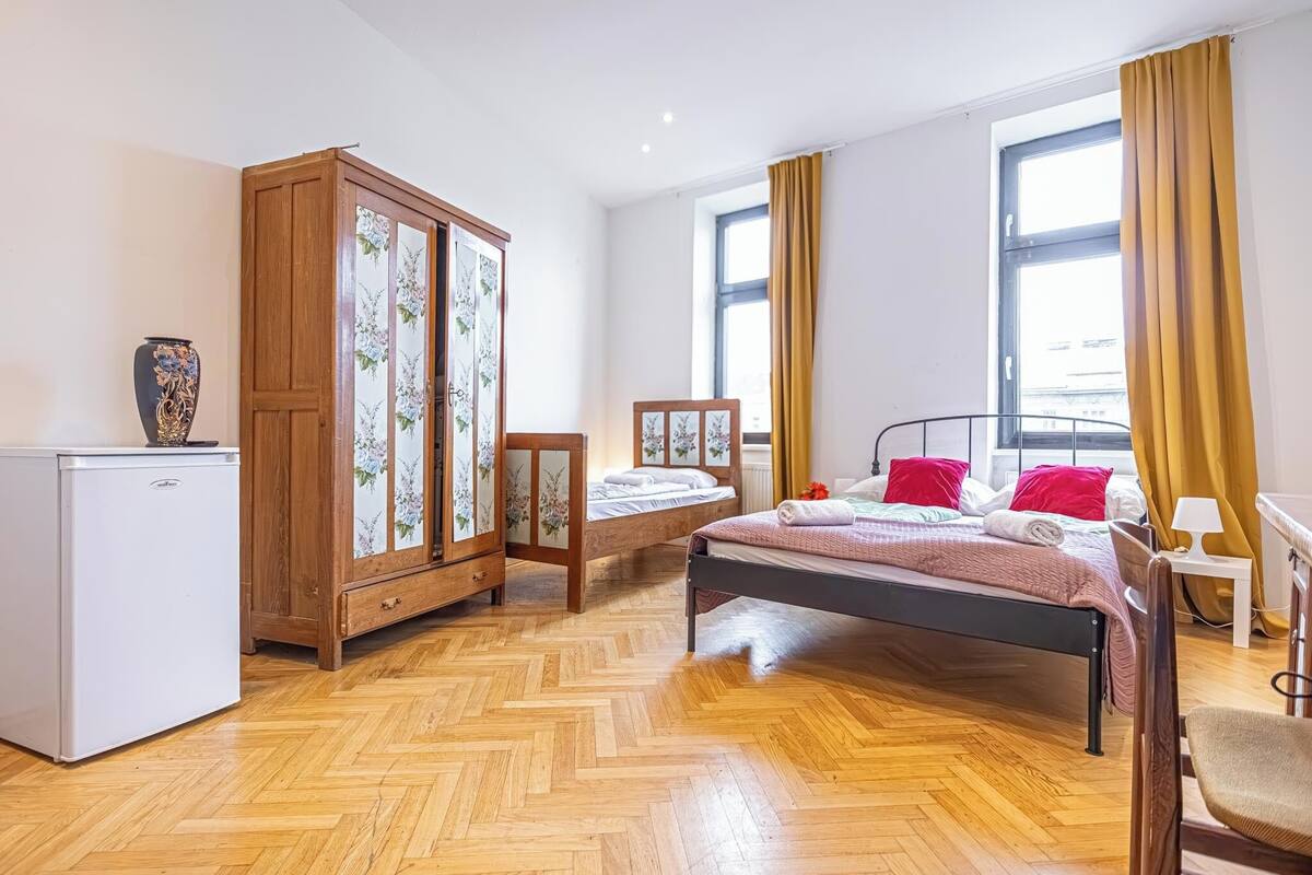 A bedroom with a bed, a wardrobe, a small table, and a desk.