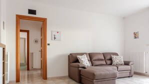 A living room with a brown sofa, a door leading to another room, and a small wall decoration. - Pandolfi House - apartment with parking space (Pescara)
