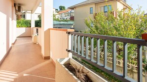 A balcony with a tiled floor, a metal railing, and a view of neighboring buildings and greenery. - Pandolfi House - apartment with parking space (Pescara)