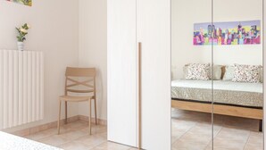 A bedroom with a bed, a chair, a radiator, and a painting on the wall. - Pandolfi House - apartment with parking space (Pescara)